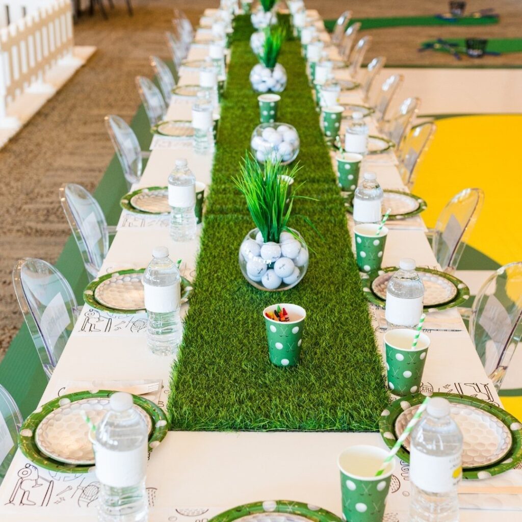 Golf themed party table with green grass runner, golf balls, and green cups