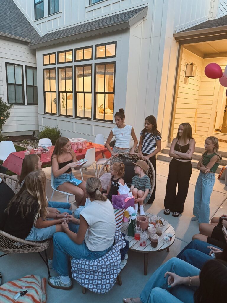 Teenage girls gathering on a patio for a birthday party with snacks and balloons.
