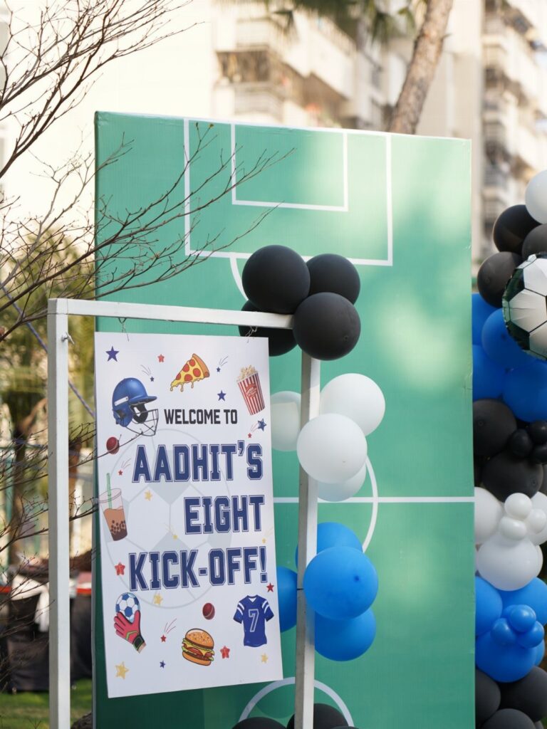 Sports themed birthday party backdrop with soccer field design and blue and black balloons