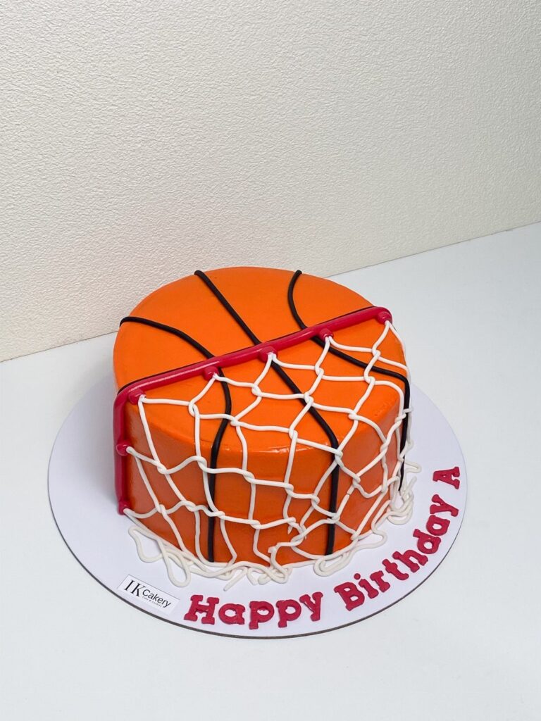 Basketball birthday cake with orange frosting, black lines, and a white icing net.