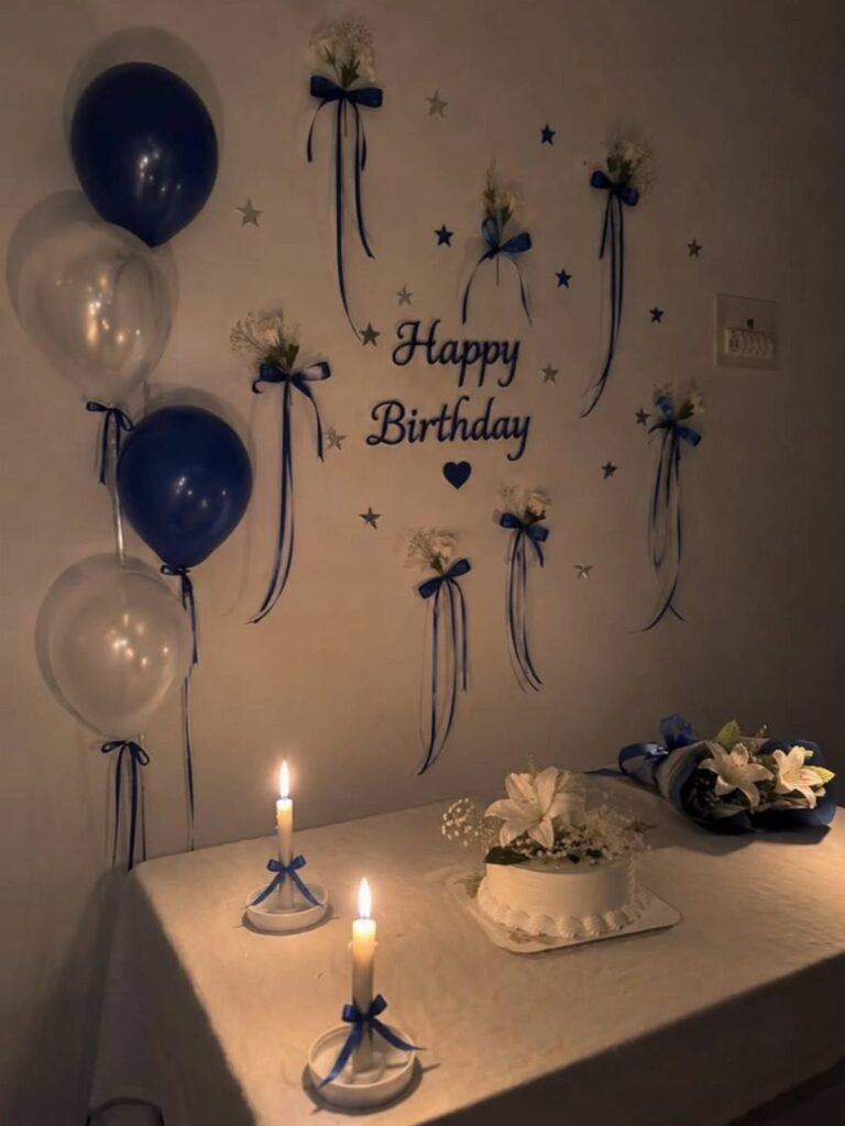 Birthday party setup with blue balloons, a white cake, and wall decorations.