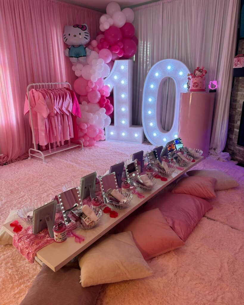Pink spa party setup with illuminated number 10, robes, and grooming stations.