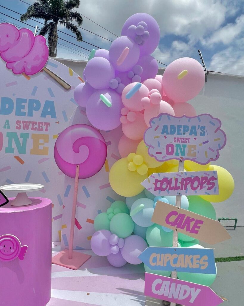 Candy themed birthday party decorations with pastel balloons and giant lollipop props.
