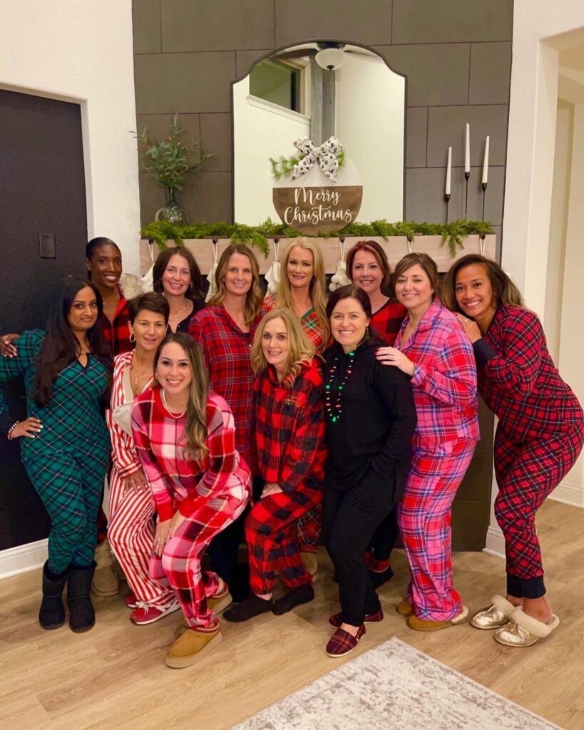 Group of women wearing colorful plaid pajamas posing in a decorated living room.