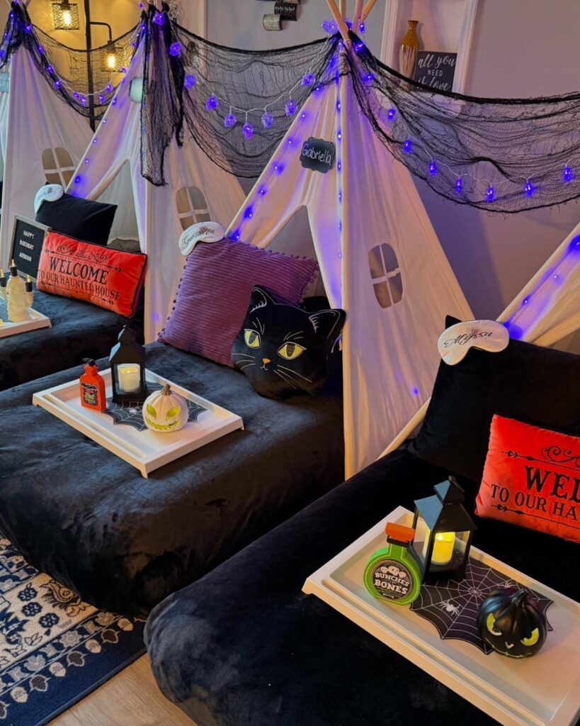 White teepee tents decorated with black cobwebs, purple lights, and Halloween themed accessories.
