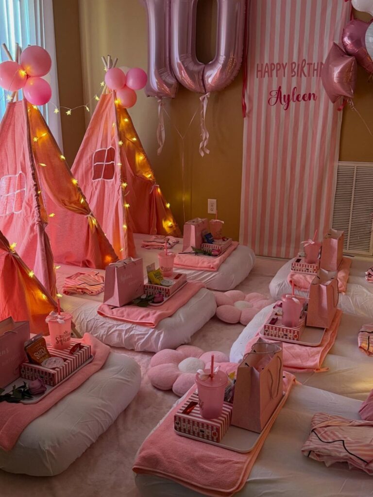 Pink teepee tents and floor mattresses with party trays for a birthday slumber party