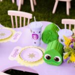 Purple party table with Tangled themed plates, cups, and green chameleon favors.