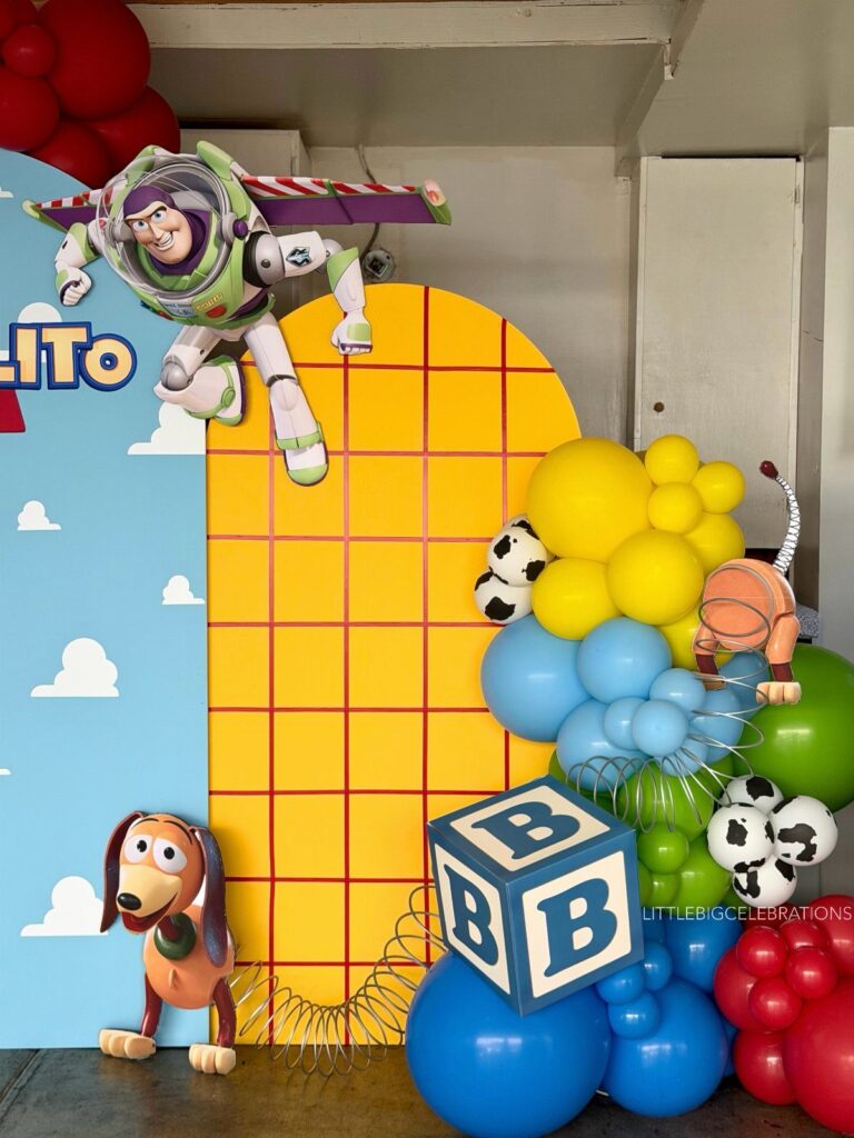 Toy Story party decorations with Buzz Lightyear, Slinky Dog, and colorful balloon arches.