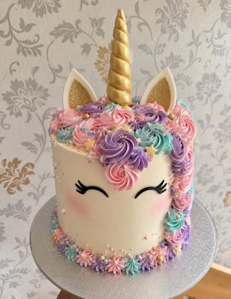 Unicorn birthday cake with gold horn, colorful frosting mane, and gold star decorations.